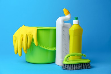 Photo of Green bucket, cleaning supplies and tools on light blue background