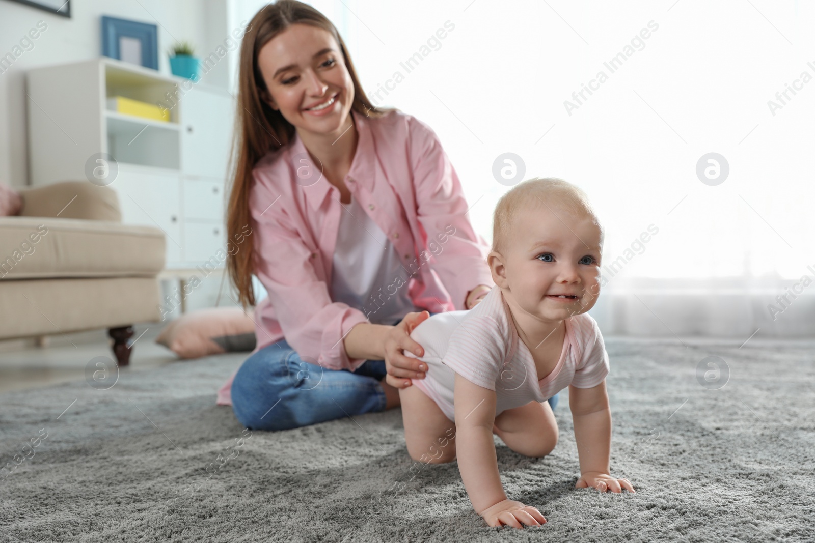 Photo of Adorable little baby crawling near mother at home