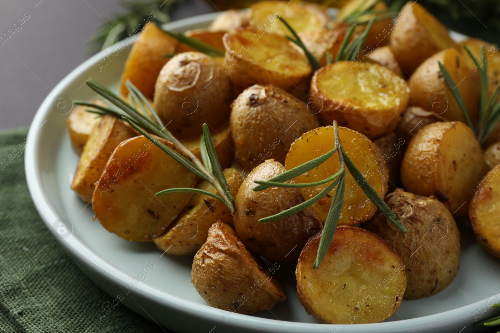 Photo of Delicious baked potatoes with rosemary on plate, closeup
