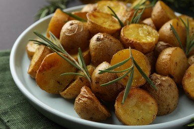 Delicious baked potatoes with rosemary on plate, closeup