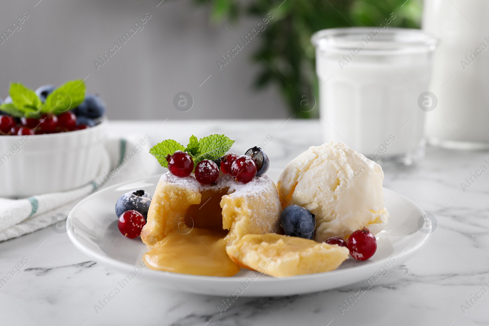 Photo of Tasty vanilla fondant with white chocolate, berries and ice cream on white marble table