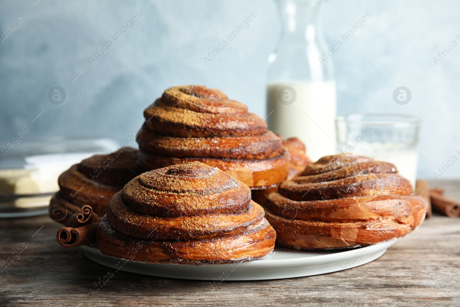 Photo of Plate with baked cinnamon rolls on wooden table