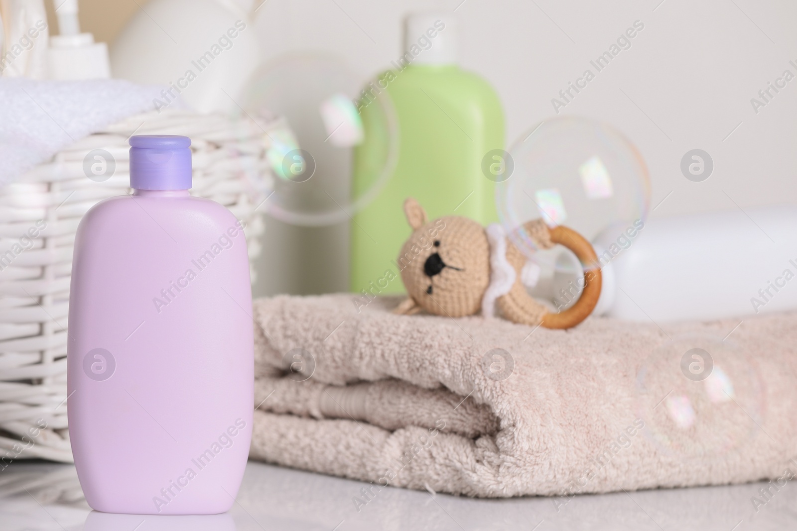 Photo of Baby cosmetic products, towel, toy and soap bubbles on light background