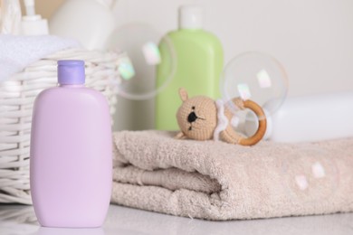 Baby cosmetic products, towel, toy and soap bubbles on light background