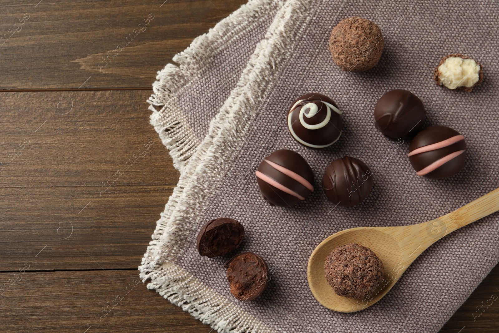 Photo of Many different delicious chocolate truffles on wooden table, top view. Space for text