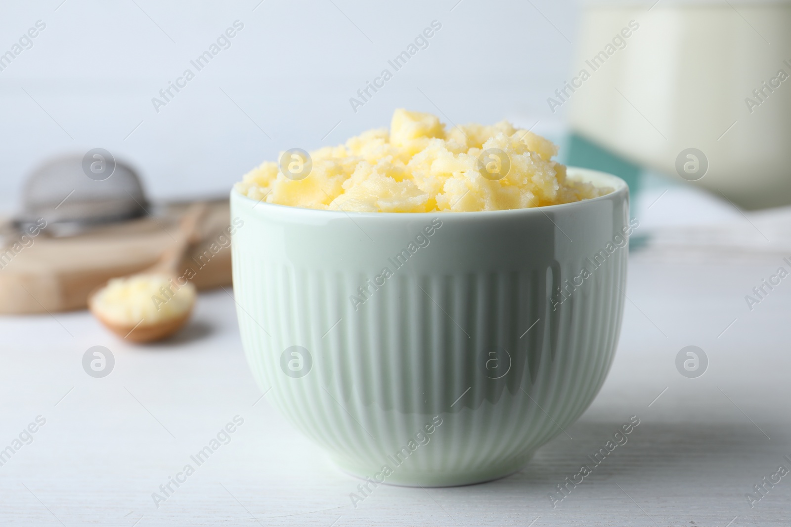 Photo of Bowl of Ghee butter on white wooden table, closeup