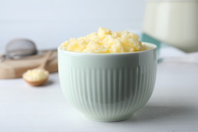 Photo of Bowl of Ghee butter on white wooden table, closeup