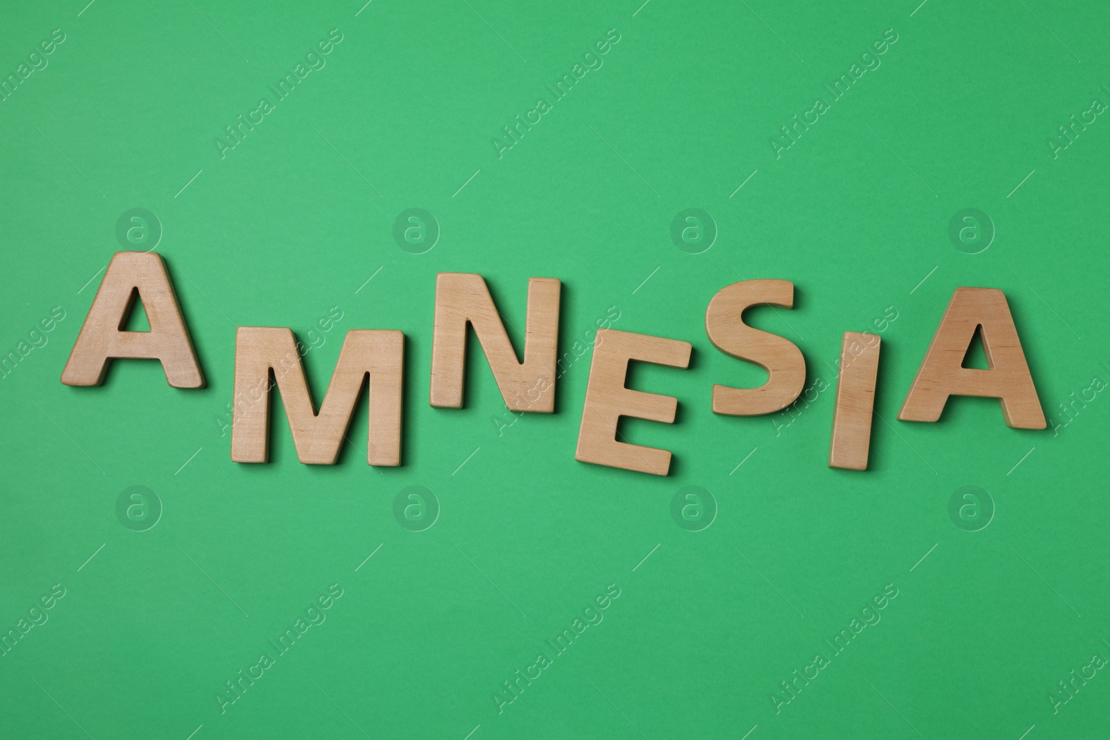 Photo of Word Amnesia made of wooden letters on green background, flat lay