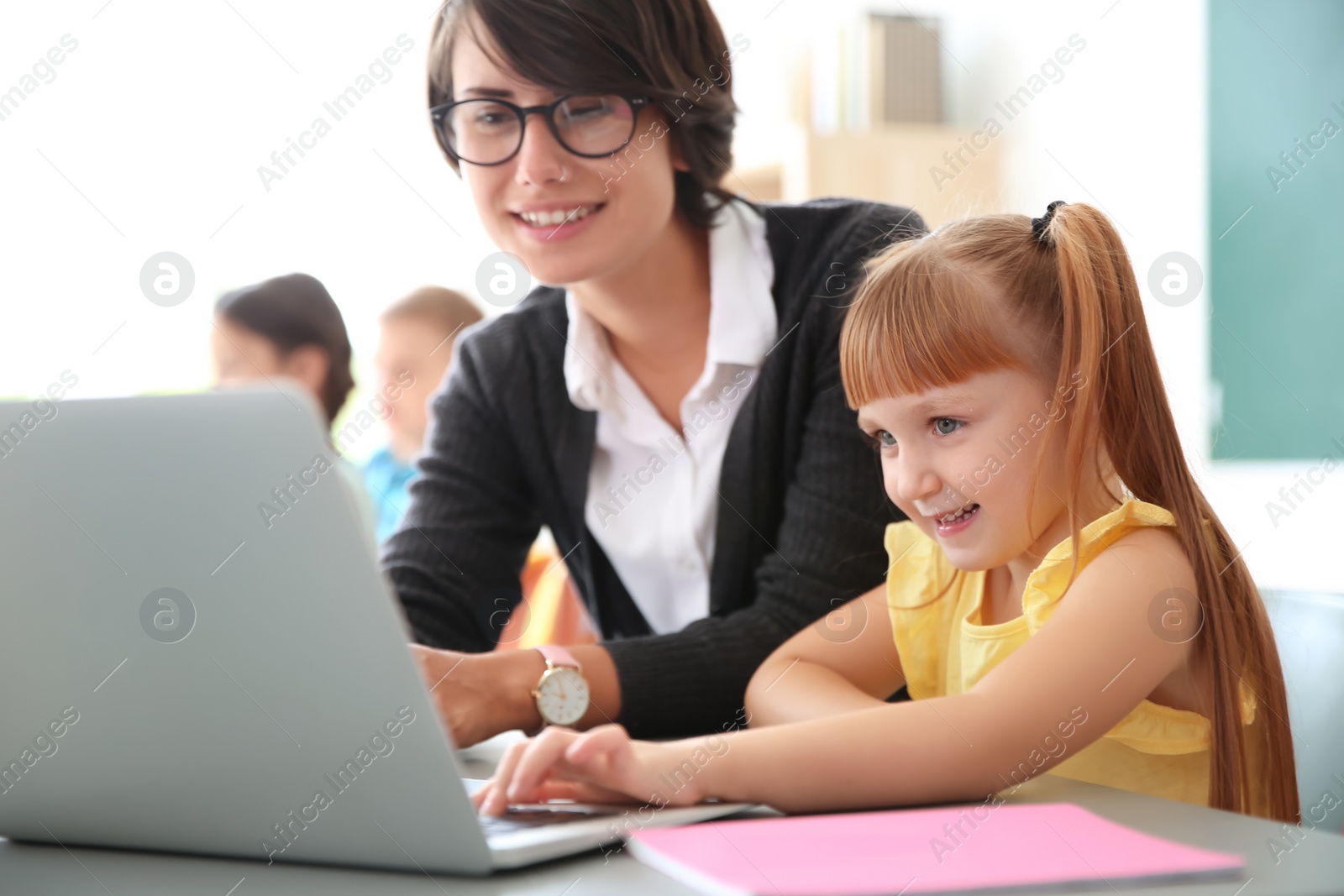 Photo of Female teacher helping child with assignment at school