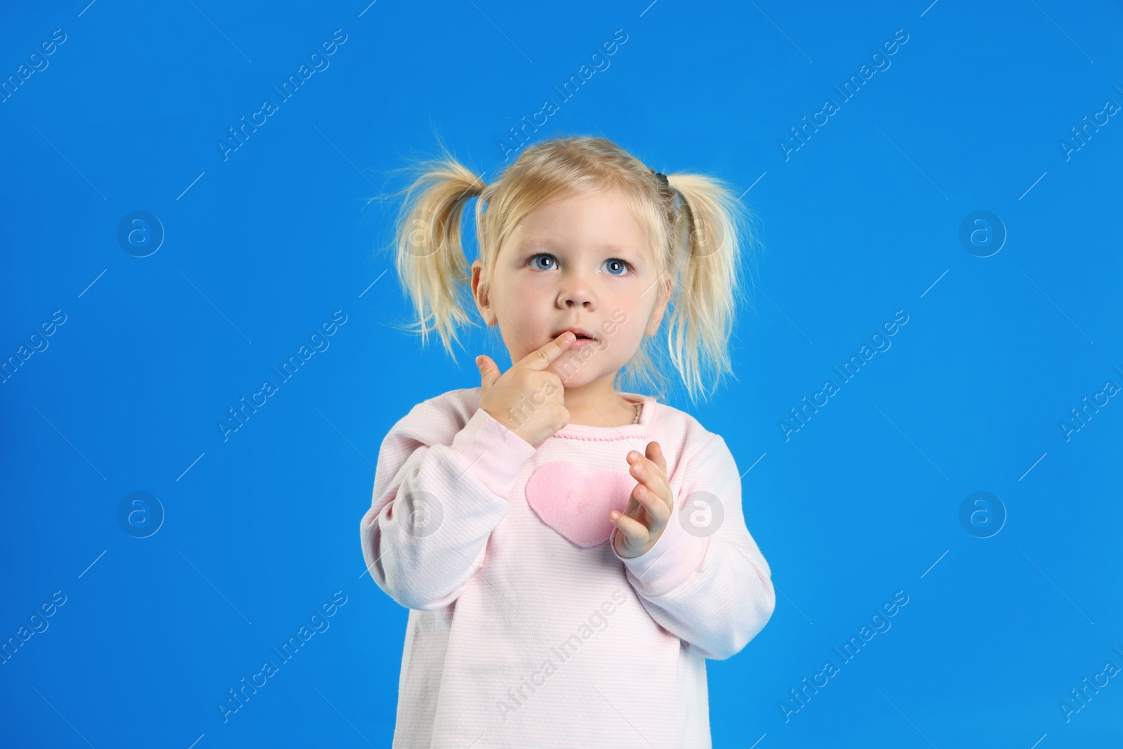 Photo of Cute little girl posing on light blue background