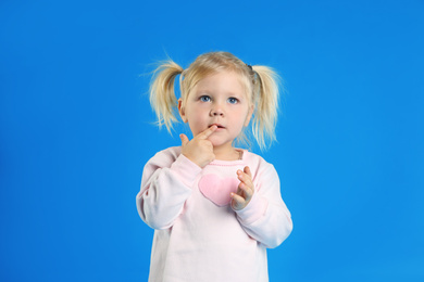 Cute little girl posing on light blue background