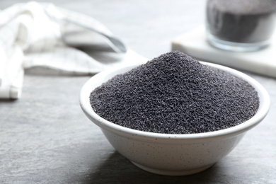 Photo of Poppy seeds in bowl on grey table