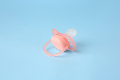 Photo of One new baby pacifier on light blue background