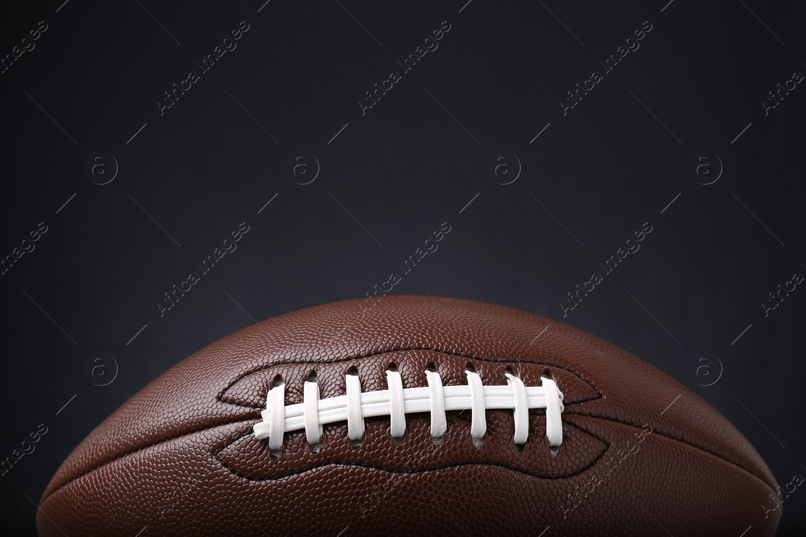 Photo of American football ball on black background, closeup. Space for text