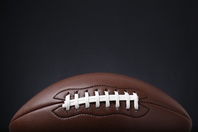 Photo of American football ball on black background, closeup. Space for text