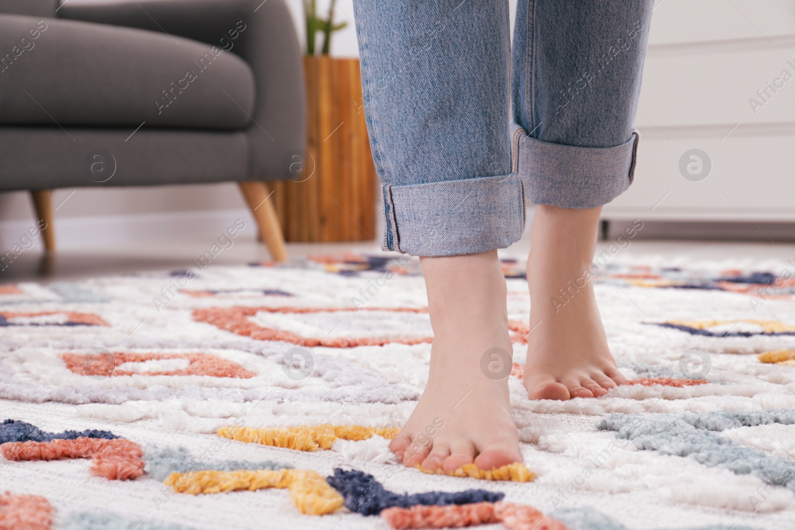 Photo of Woman standing on soft carpet at home, closeup