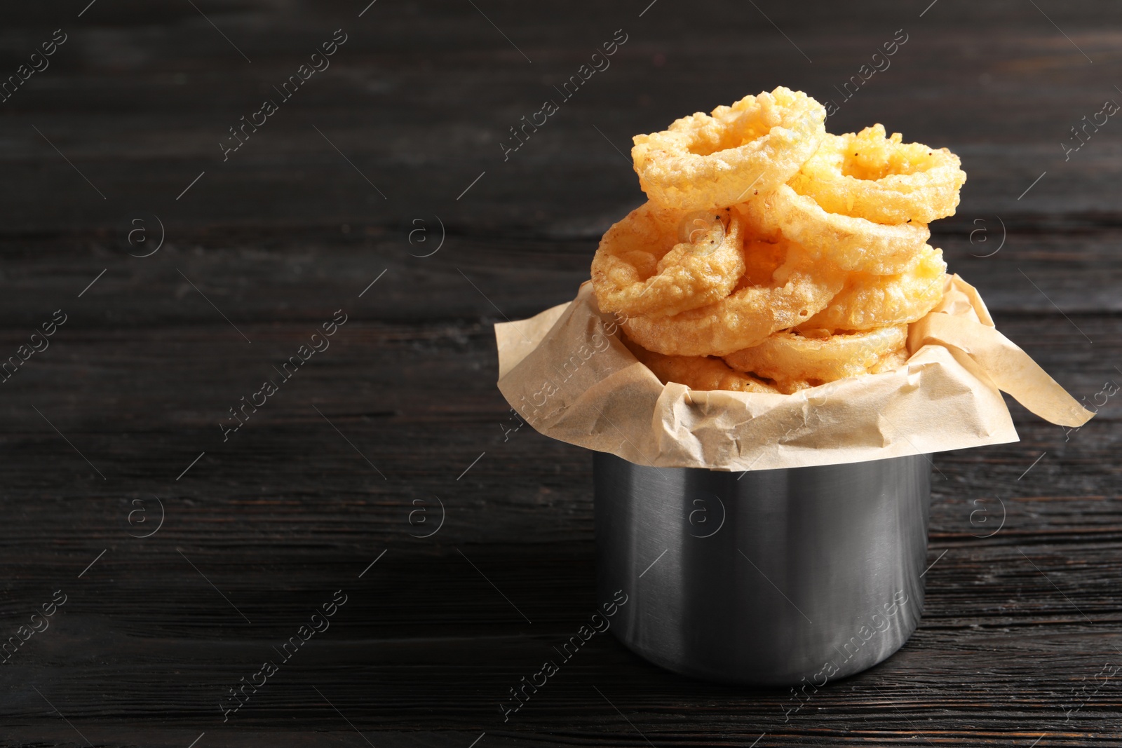 Photo of Dishware with homemade crunchy fried onion rings on wooden table. Space for text