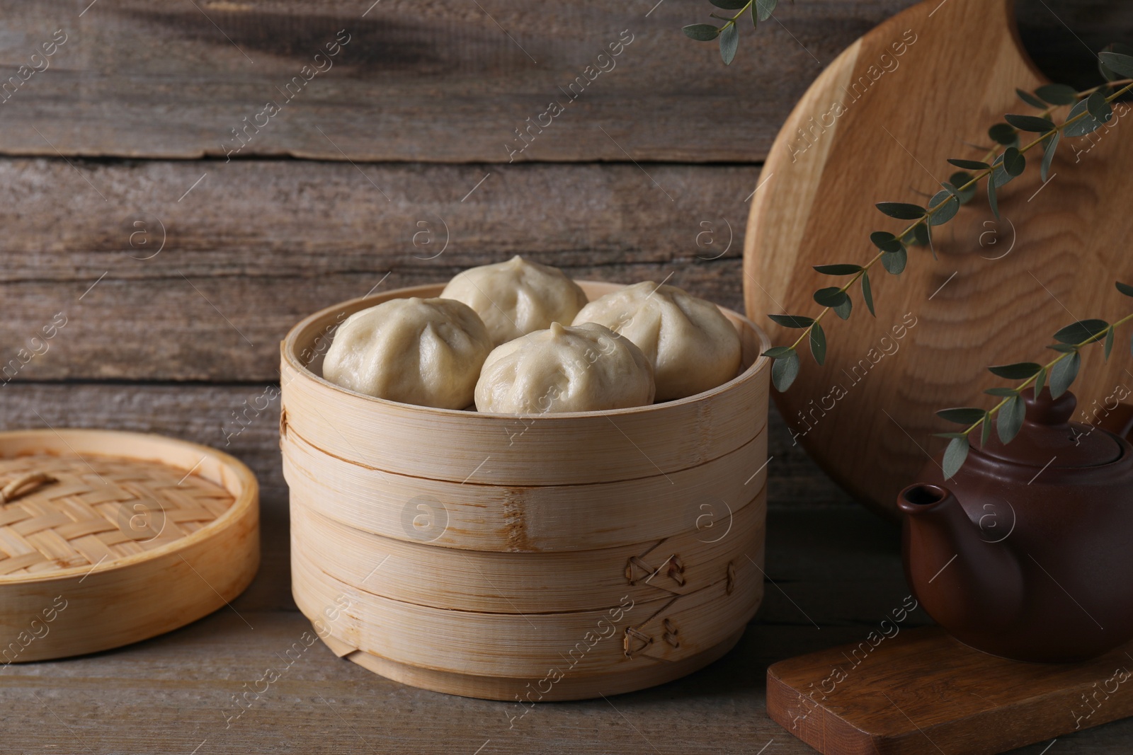 Photo of Delicious bao buns (baozi) on wooden table, closeup