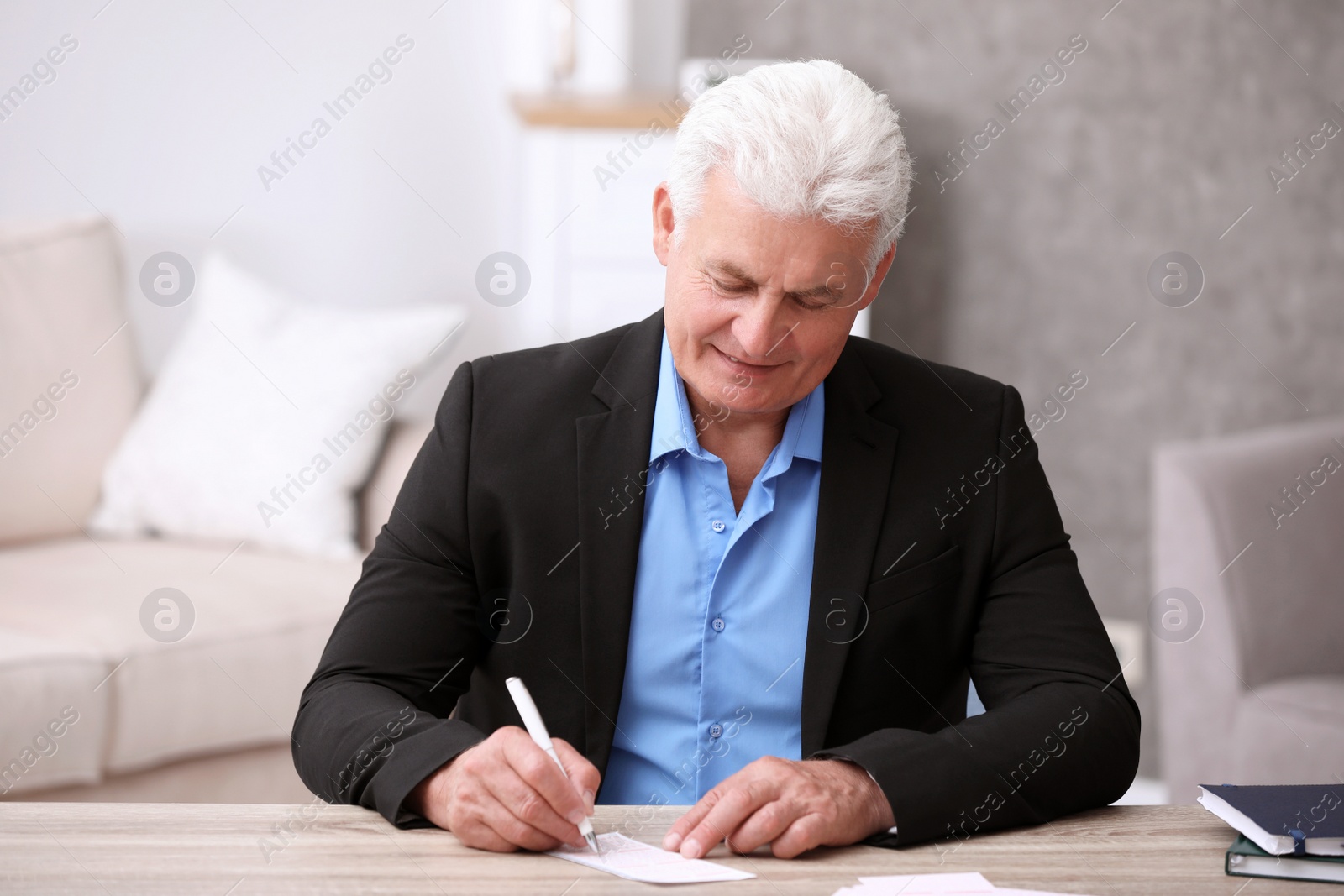 Photo of Portrait of senior man filling out lottery ticket at table