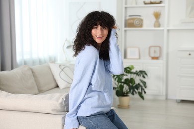 Happy young woman in stylish light blue sweater indoors