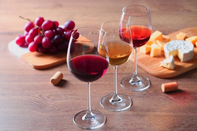 Glasses with different wines and appetizers on wooden table