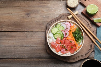 Photo of Delicious poke bowl with salmon and vegetables served on wooden table, flat lay. Space for text