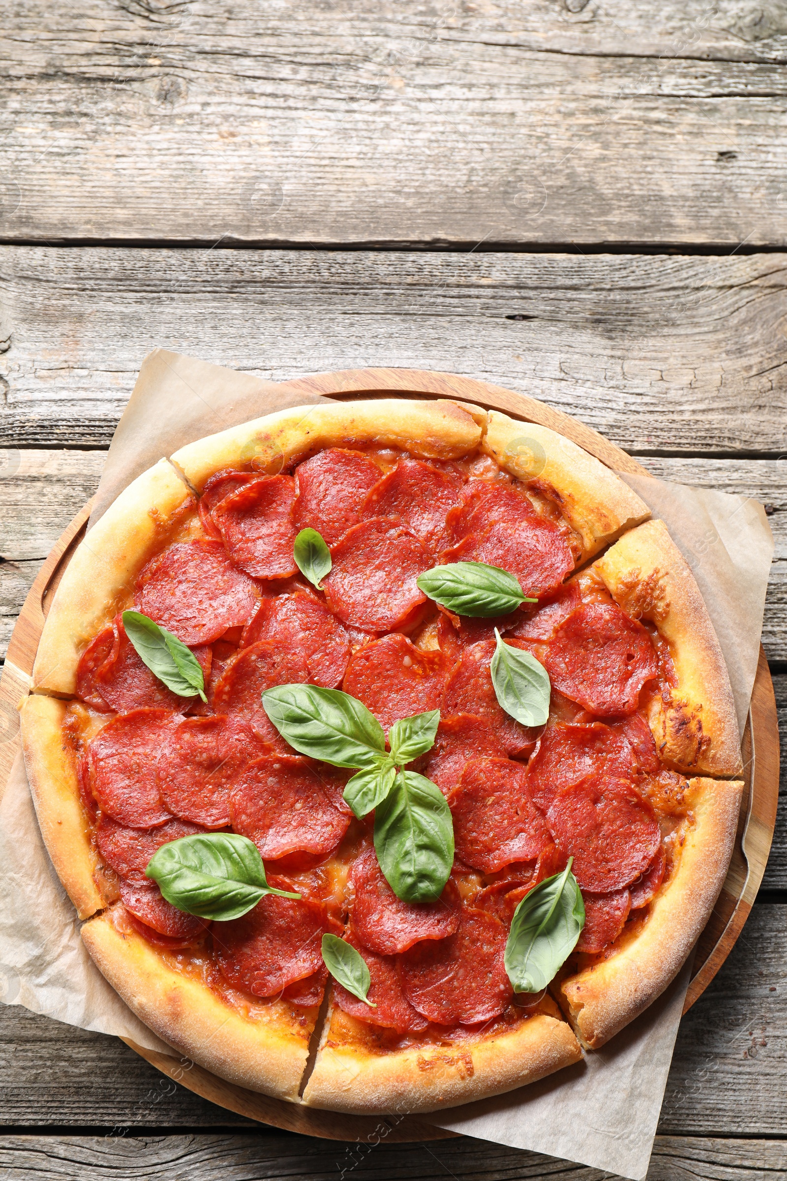 Photo of Tasty pepperoni pizza with basil on wooden table, top view. Space for text