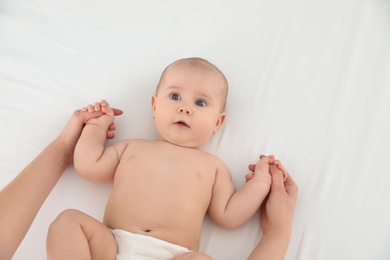 Mother and her cute child on white bed, top view. Baby massage and exercises