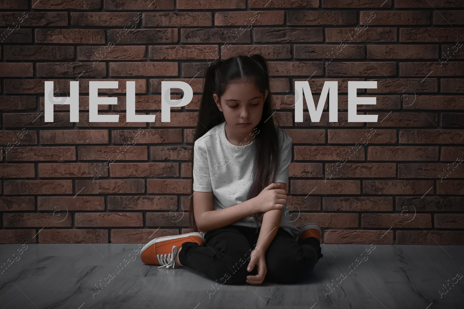 Image of Sad little girl near brick wall and text HELP ME