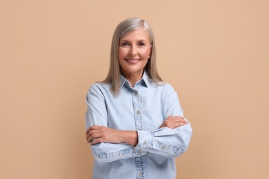 Portrait of beautiful middle aged woman on beige background