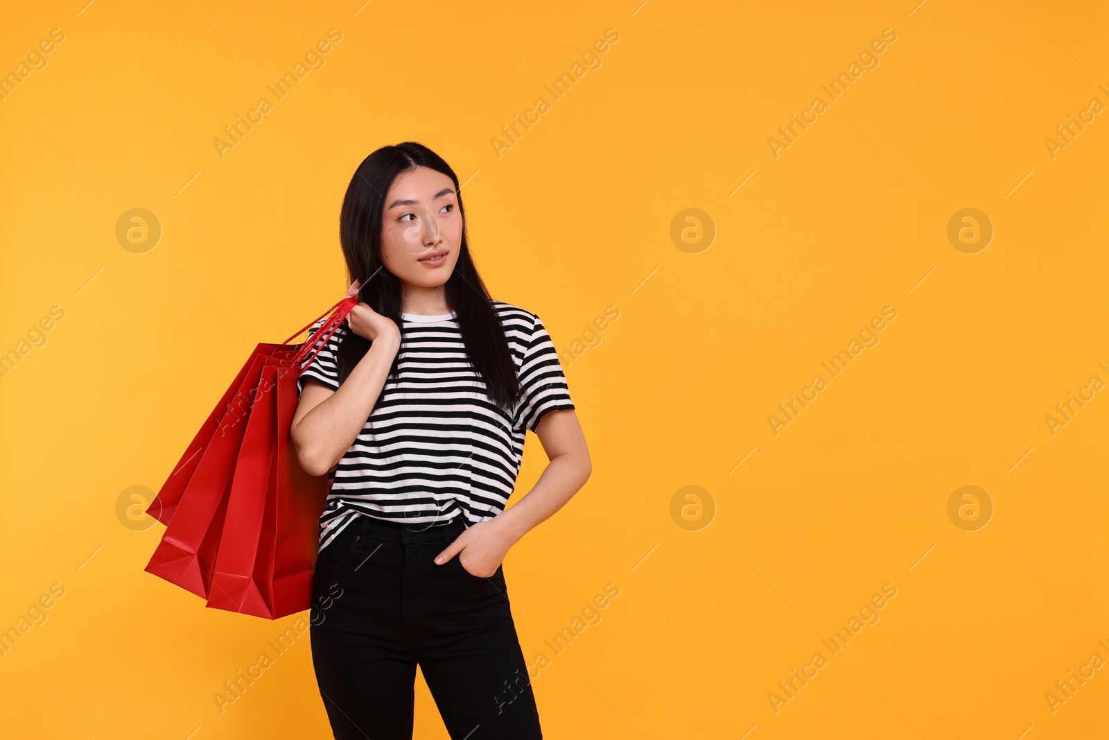 Photo of Beautiful woman with shopping bags on yellow background. Space for text