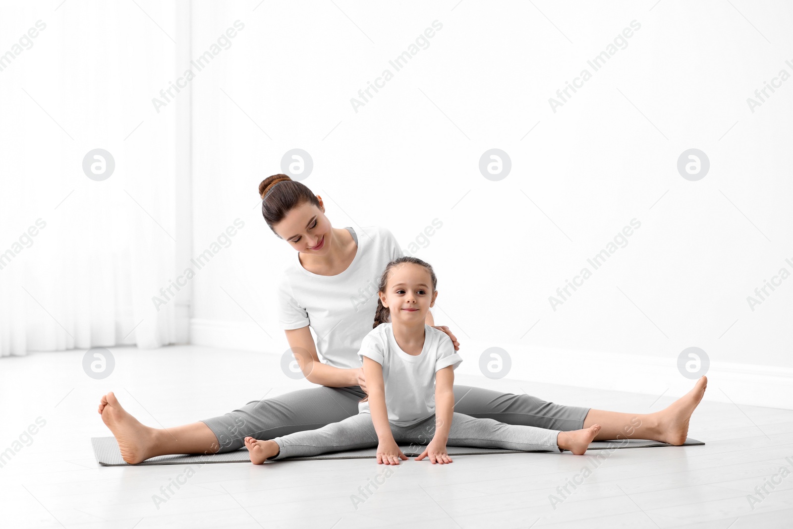 Photo of Young mother with little daughter practicing yoga at home