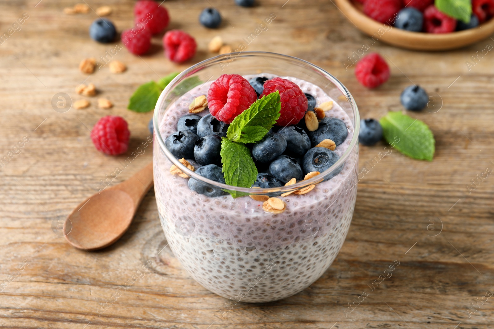 Photo of Delicious chia pudding with berries, granola and wooden table