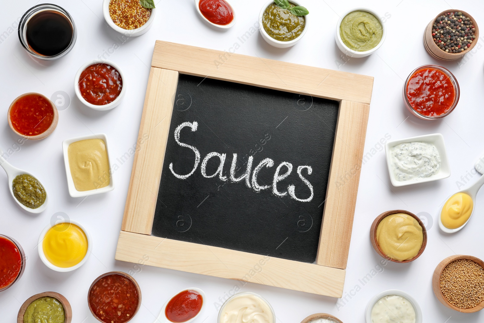 Photo of Small blackboard with word Sauces and different dressings on white background, flat lay