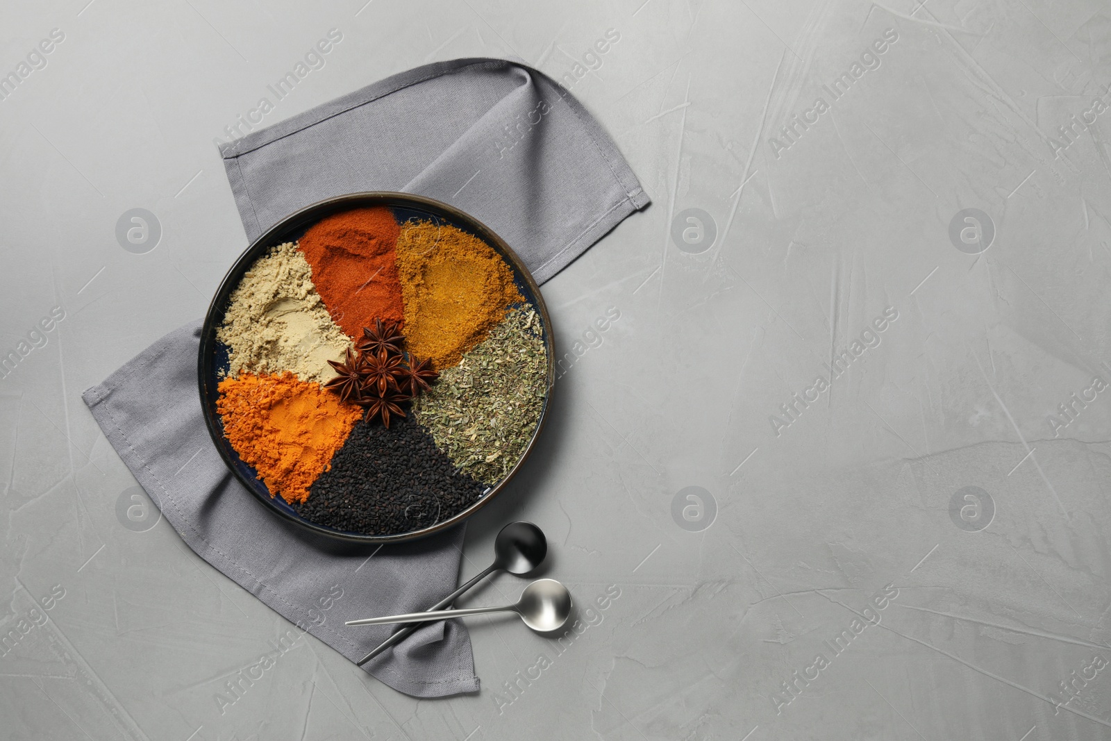 Photo of Plate with different spices on light grey table, flat lay. Space for text