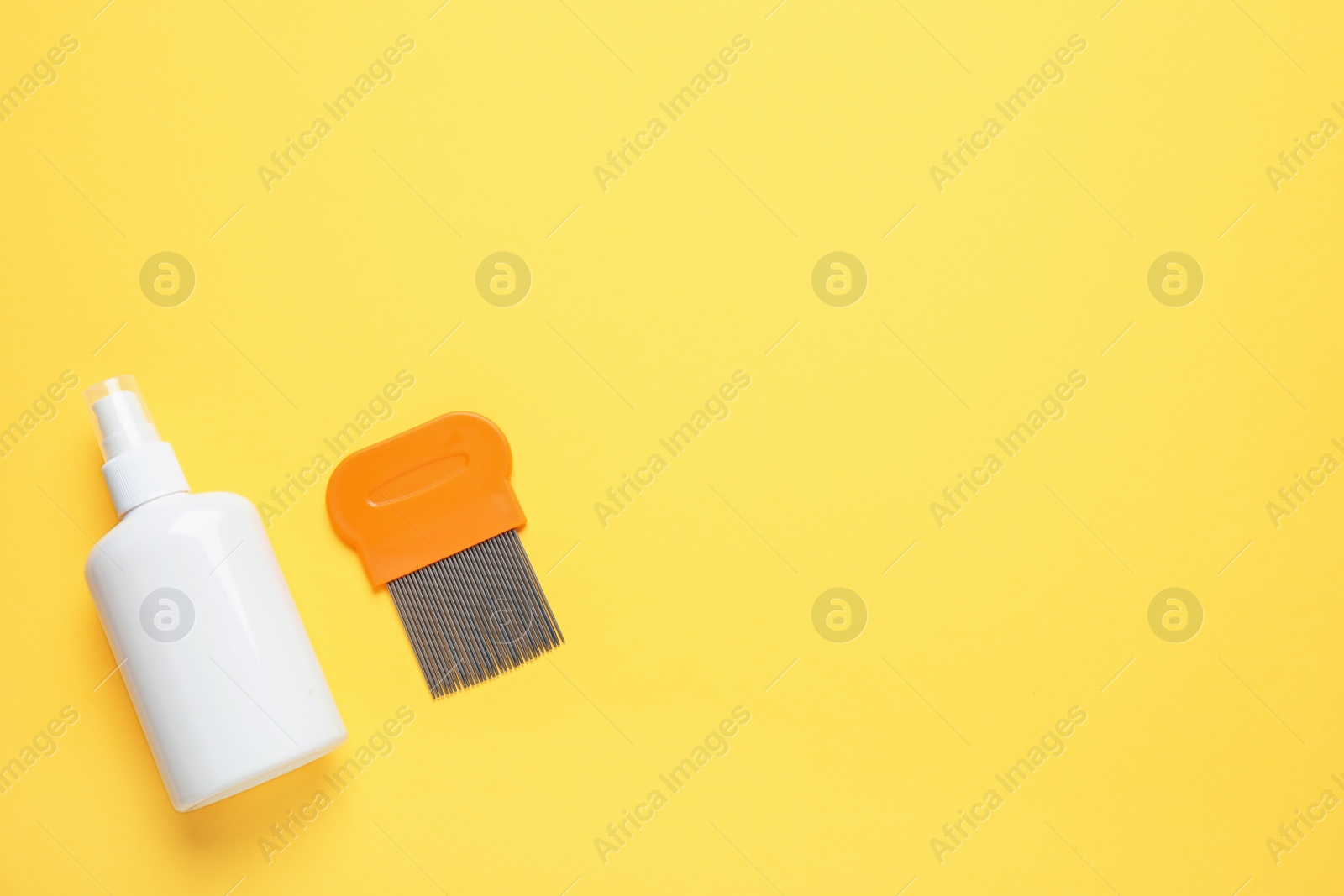 Photo of Spray and metal comb for anti lice treatment on yellow background, flat lay. Space for text