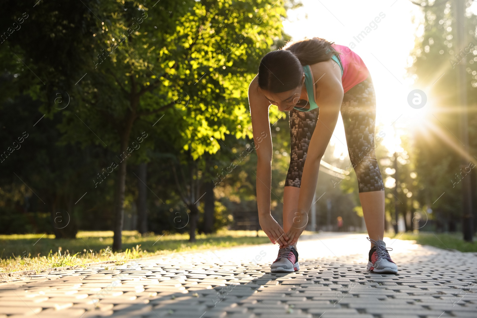 Photo of Young woman stretching before morning run in park. Space for text