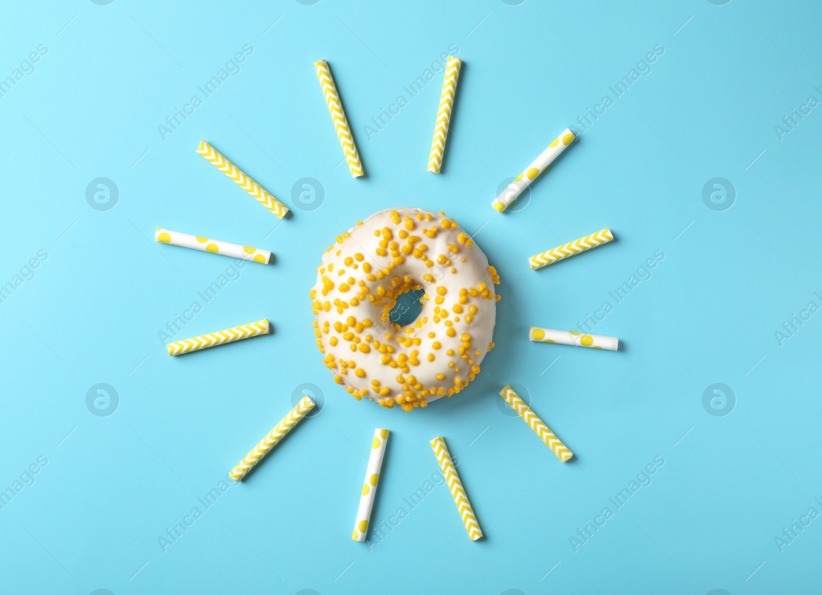 Photo of Sun made with donut and straws on light blue background, flat lay