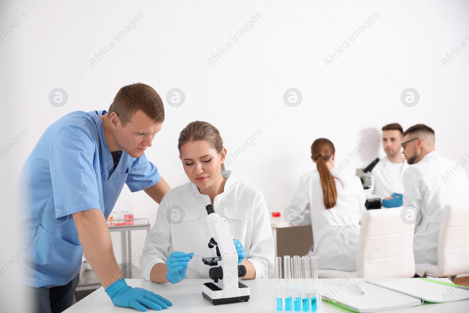 Photo of Medical students working with microscope in modern laboratory