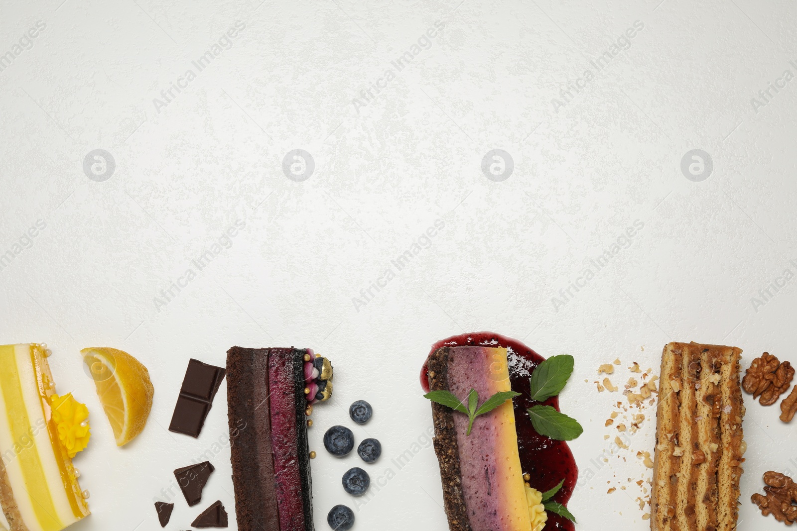 Photo of Flat lay composition with different tasty cakes on light table, space for text