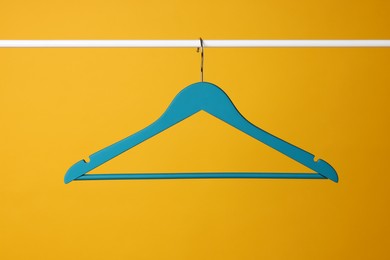 Photo of Empty clothes hanger on metal rail against yellow background