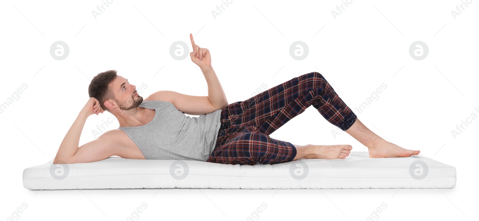 Photo of Man lying on soft mattress and pointing upwards against white background