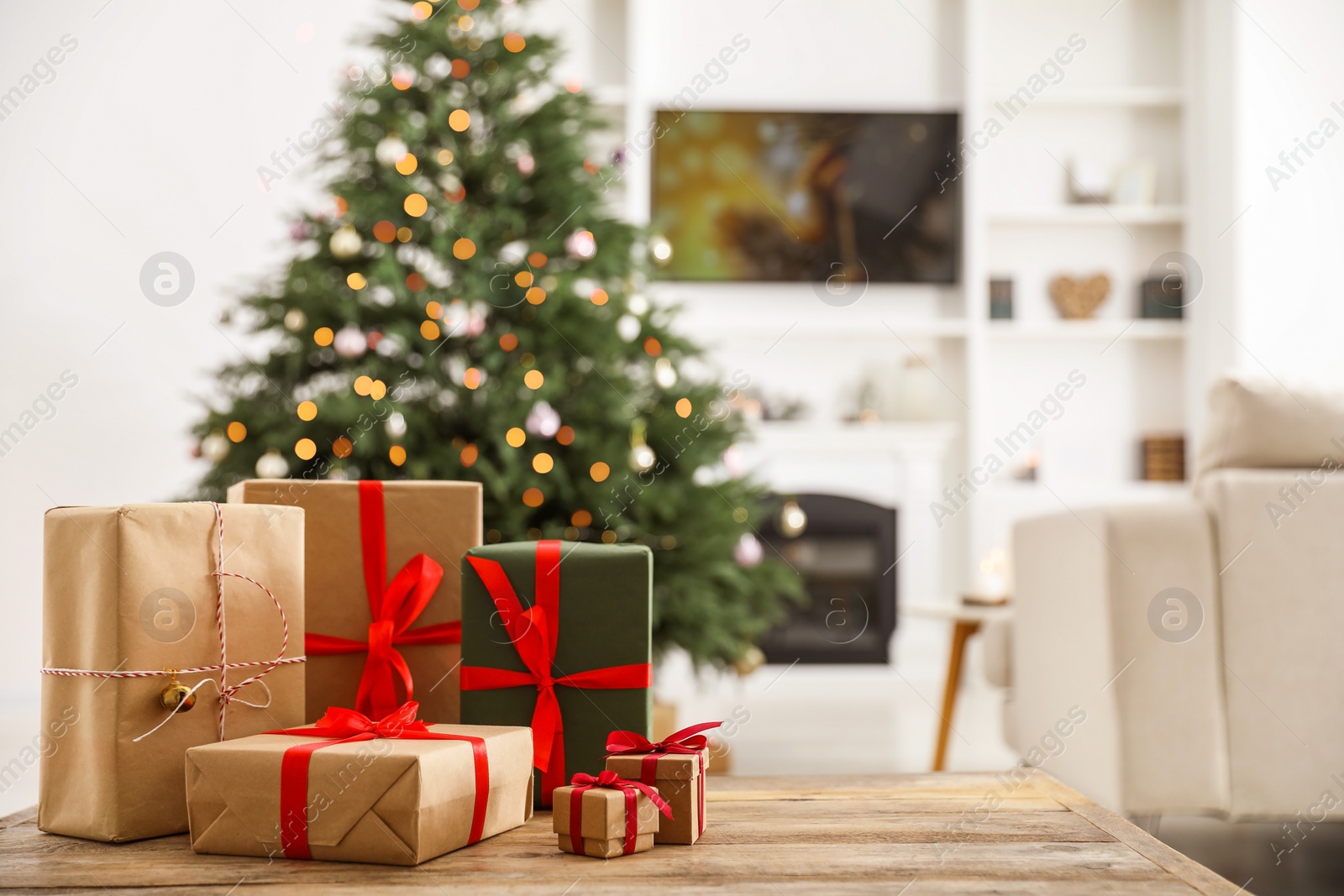 Photo of Beautifully wrapped Christmas gifts on wooden table indoors, space for text