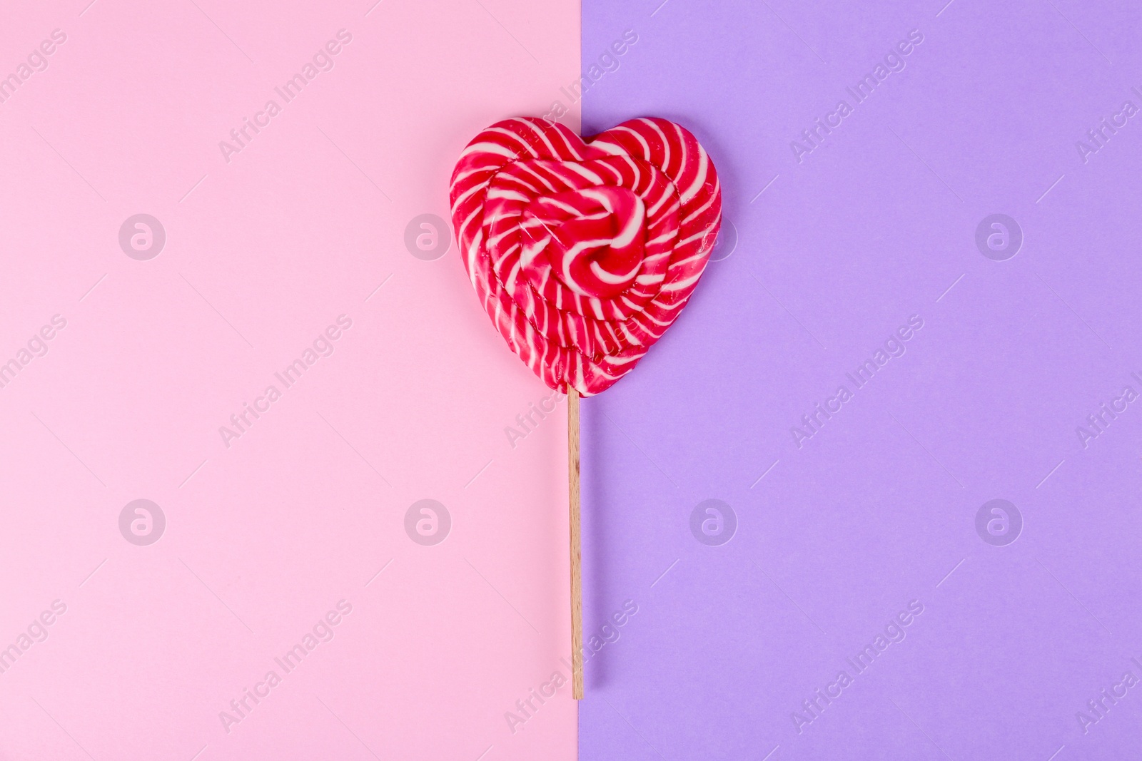 Photo of Heart shaped lollipop on color background, top view. Sweet love