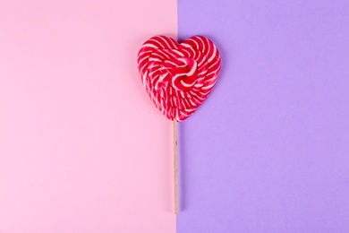 Photo of Heart shaped lollipop on color background, top view. Sweet love