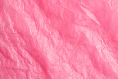 Crumpled pink plastic bag as background, top view