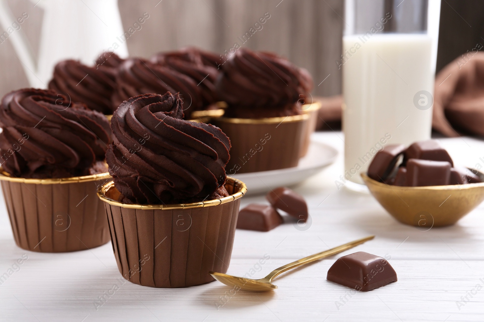 Photo of Delicious cupcake and chocolate pieces on white wooden table