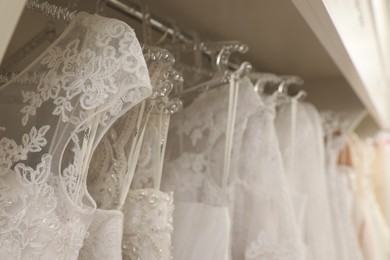 Different wedding dresses on hangers in boutique, closeup