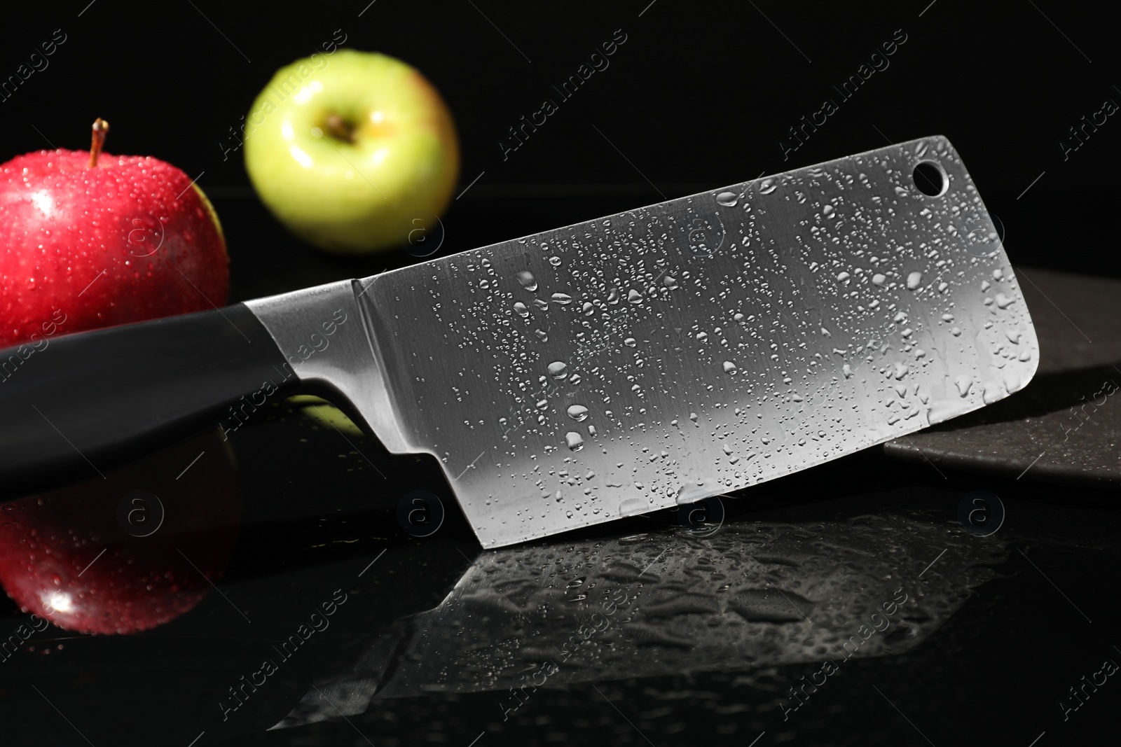 Photo of Cleaver and apples on wet black surface