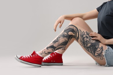 Woman with cool tattoos on grey background, closeup